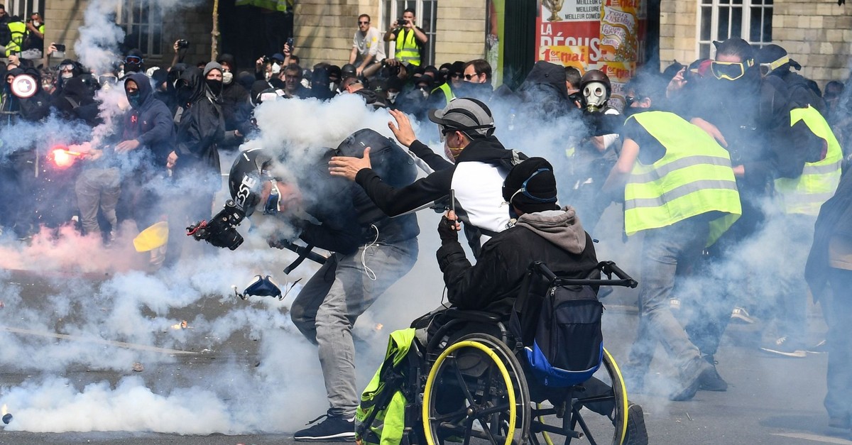 A cameraman reacts as he is hit by a tear gas canister as a u201cyellow vestu201d protester goes to help him during clashes with police in Paris, May 1, 2019. 