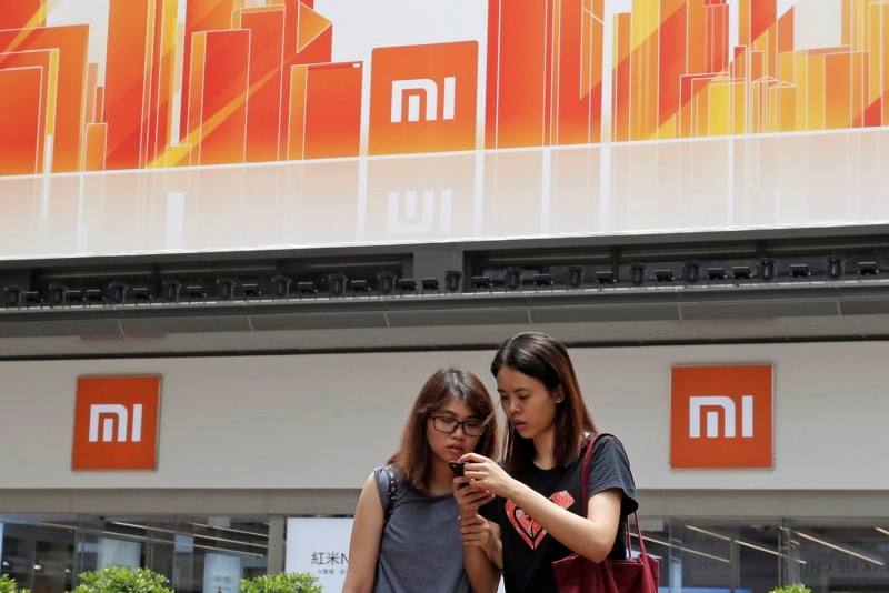 In this Wednesday, June 20, 2018, photo, people use their smartphone outside a Xiaomi store in Hong Kong. (AP Photo)