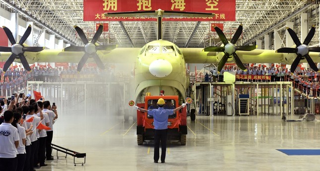Chinese workers wave national flags as the Amphibious aircraft AG600 is rolled off a production line in Zhuhai in south China’s Guangdong Province. (AP Photo)