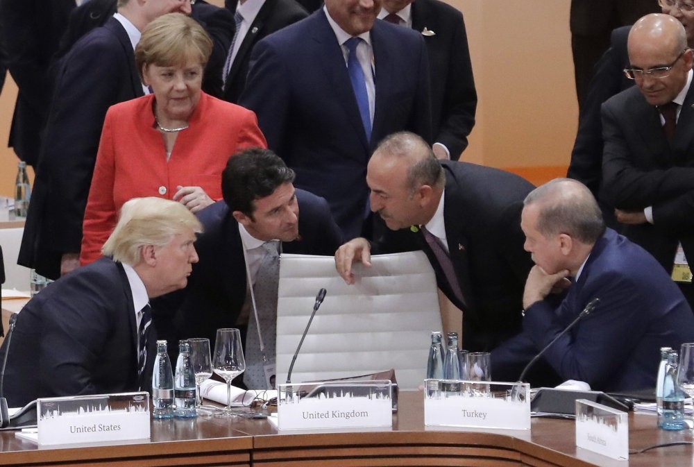 German Chancellor Angela Merkel looks on as U.S. President Donald Trump (L) talks to Foreign Minister Mevlu00fct u00c7avuu015fou011flu and President Recep Tayyip Erdou011fan (R) prior to the first working session on the first day of G-20 summit, Hamburg, July 7, 2017.