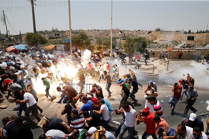 Palestinians react following tear gas that was shot by Israeli forces after Friday prayer on a street outside Jerusalem's Old city July 21, 2017. (Reuters Photo)