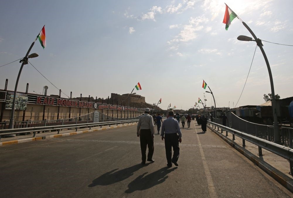 Iraqis walk down a street flying KRG flags in the Iraqi city of Kirkuk on Sept. 18. 