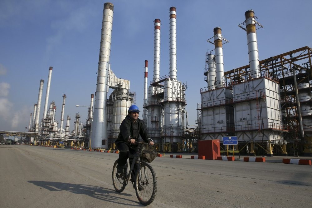 An Iranian oil worker rides a bicycle at an oil refinery, south of the capital Tehran, Iran, Dec. 22, 2014. 