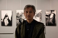 Lam Duc Hien poses in front of his photos at the exhibit. 