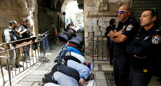 Palestinian men pray as Israeli security forces secure the Al-Aqsa mosque compou nd in Jerusalem's Old City, July 26.