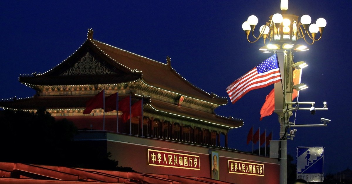 People walk under U.S. and Chinese flags at the Forbidden City during the visit by U.S. President Donald Trump in Beijing, China, November 8, 2017.