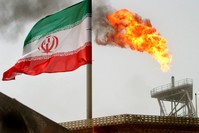 A gas flare on an oil production platform in the Soroush oil fields is seen alongside an Iranian flag in the Persian Gulf.