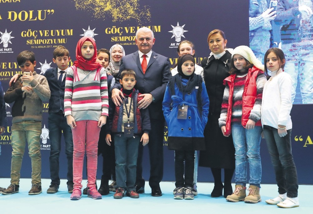 Prime Minister Binali Yu0131ldu0131ru0131m poses with refugee children at the symposium in Ankara.