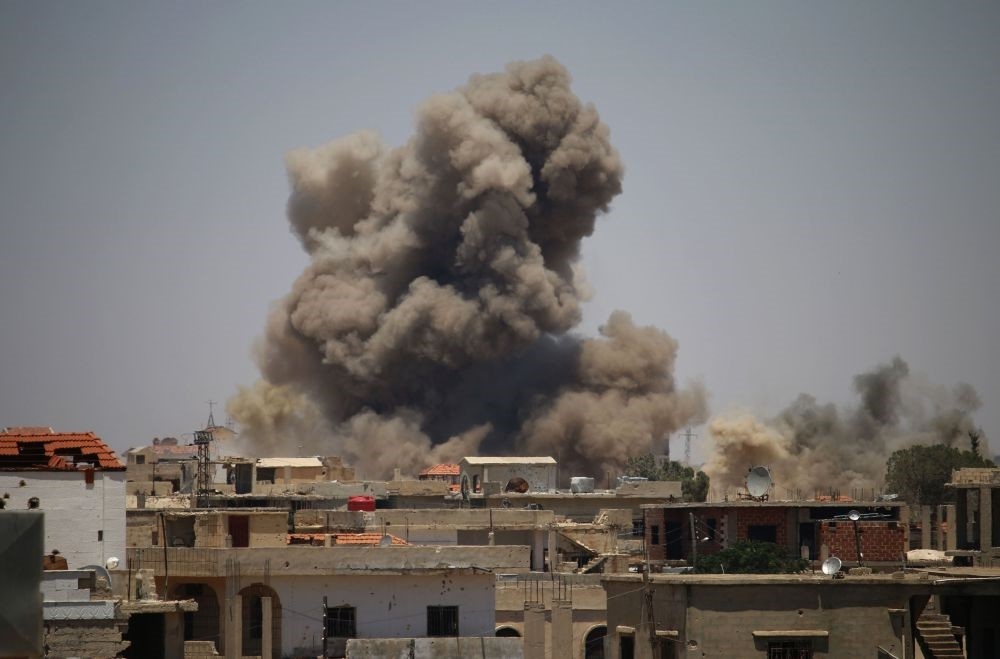 Smoke rises above buildings during an airstrike by Syrian regime forces on the town of Busra al-Harir in the eastern province of Daraa, June 24.