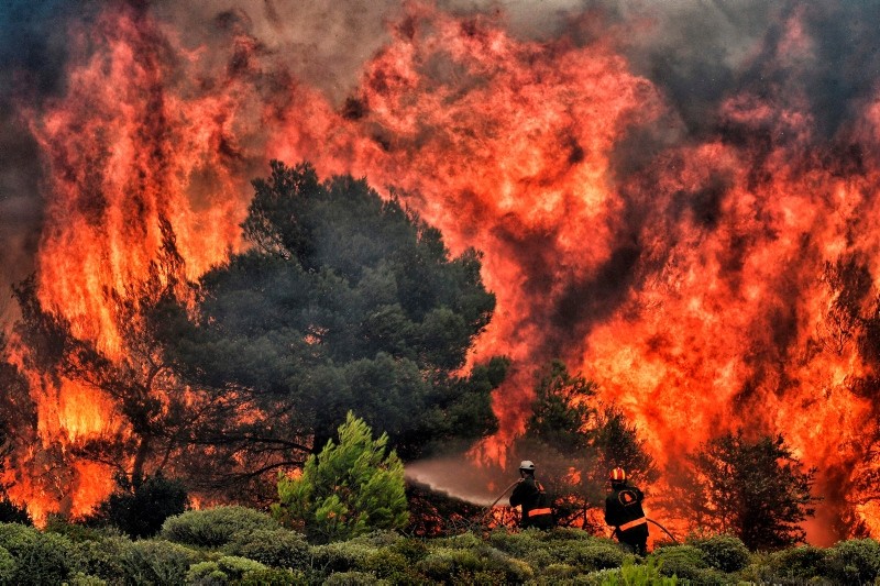 Firefighters try to extinguish flames during a wildfire at the village of Kineta, near Athens, on July 24, 2018. (AFP Photo)