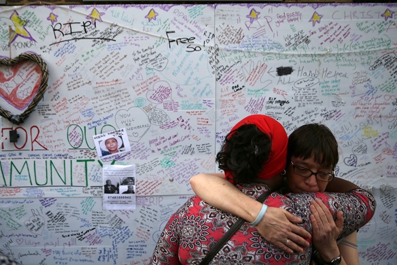 Two women embrace in front of a messages left on a wall of condolence following the blaze at Grenfell Tower, a residential tower block in west London on June 15, 2017. (AFP Photo)