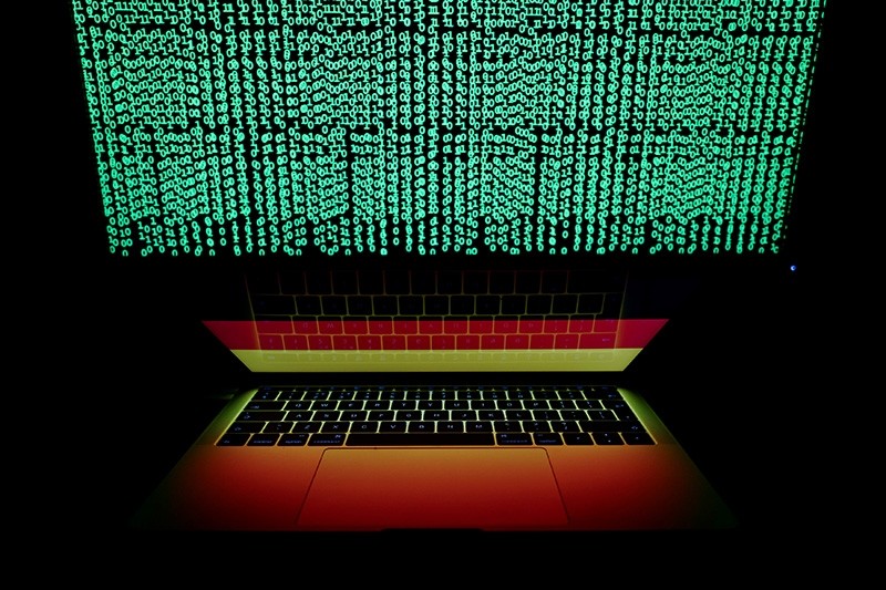 A German flag is seen on the laptop screen in front of a computer screen on which cyber code is displayed, in this illustration picture taken March 2, 2018. (Reuters Photo)