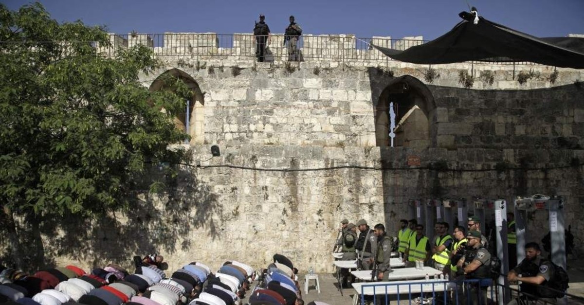 Israeli border police stand guard as Muslims pray outside the Al-Aqsa Mosque compound, Jerusalem. (AP Photo)