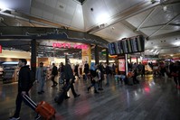 People walking in the Istanbul Airport with a flight information screen and duty free shop seen behind, Feb. 26, 2020. (AA Photo)