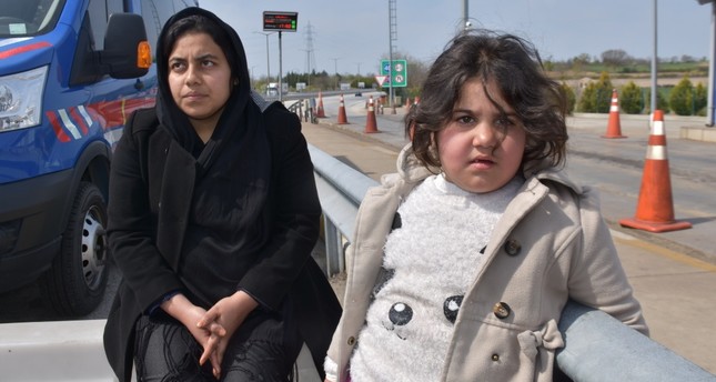 A migrant woman and a girl wait next to a gendarme vehicle after a group of migrants were stopped on the road to Edirne, April 4, 2019.